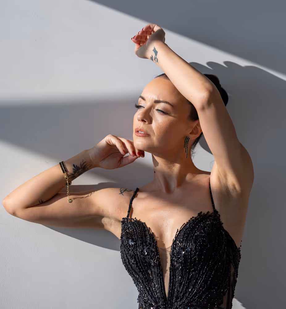 Wedding in Greece. Santorini. A shot of the bride posing for a photo, looking toward the sun. She is wearing a black wedding dress.