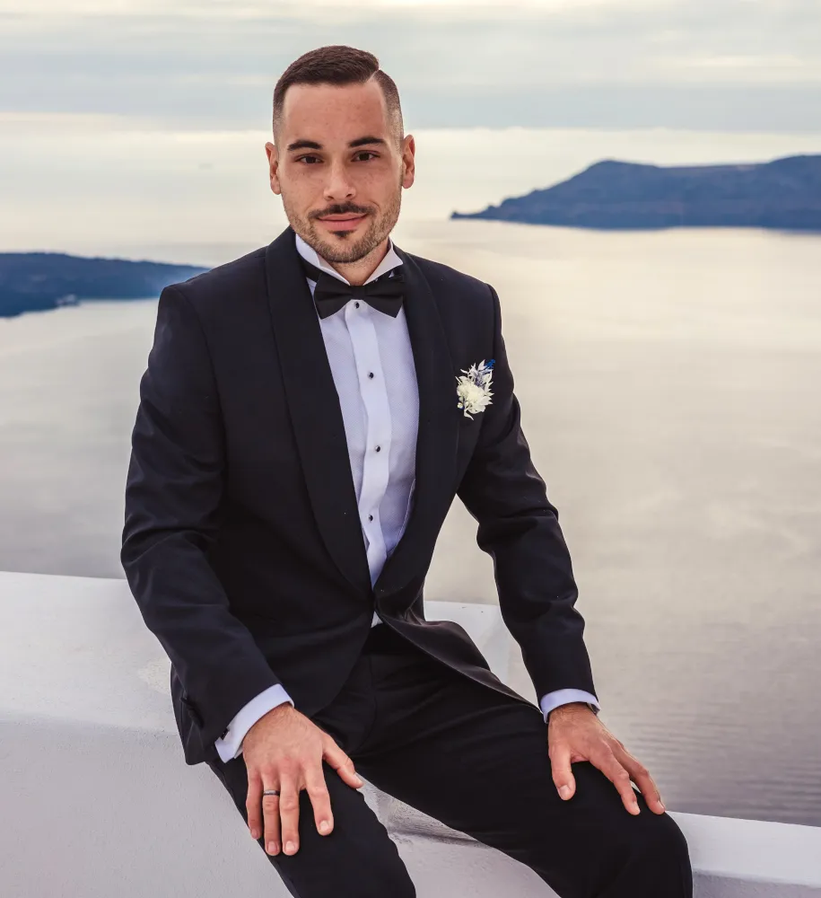A wedding in Greece. Santorini. A shot of the groom in his wedding suit on the terrace.