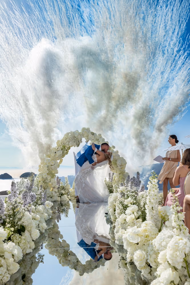 Wedding in Greece, Santorini. Young couple kissing with confetti in the background right after saying 'I do'.